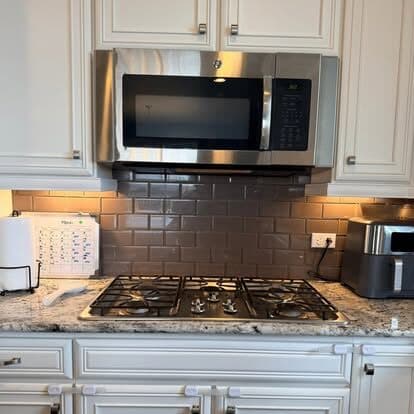Stainless gas range and tiled backsplash scrubbed free of grease